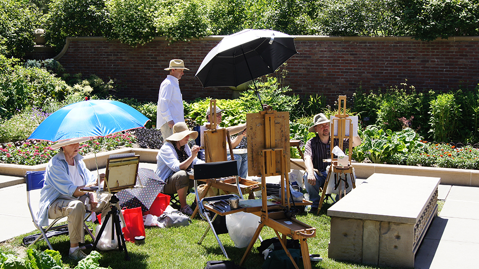 A man teaches a plein air painting class outdoors. 