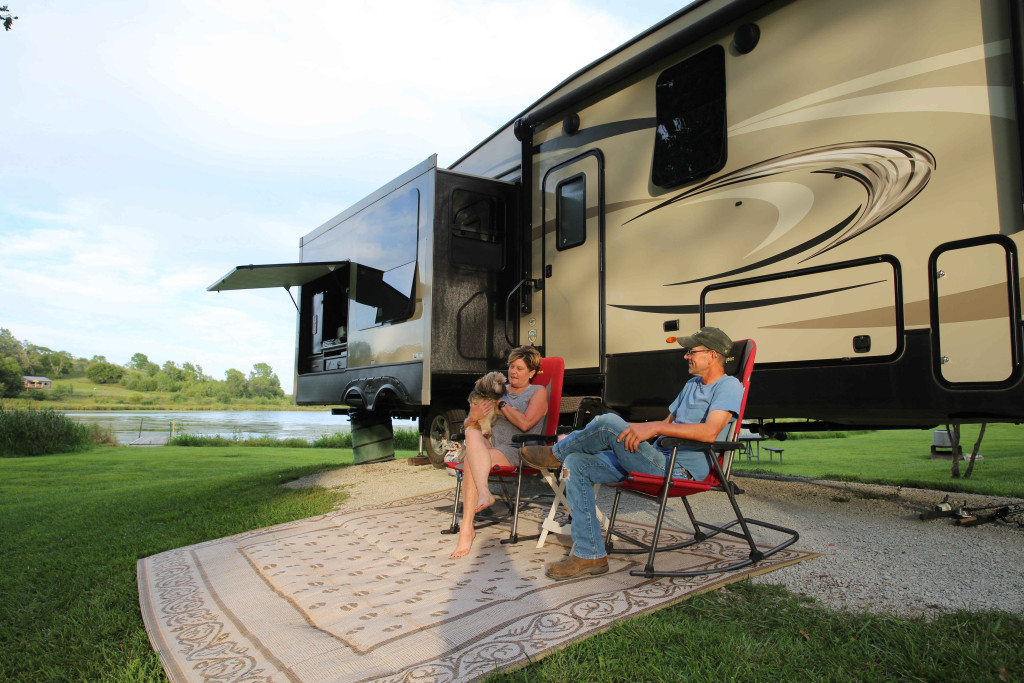 A couple sitting in front of their RV while camping.