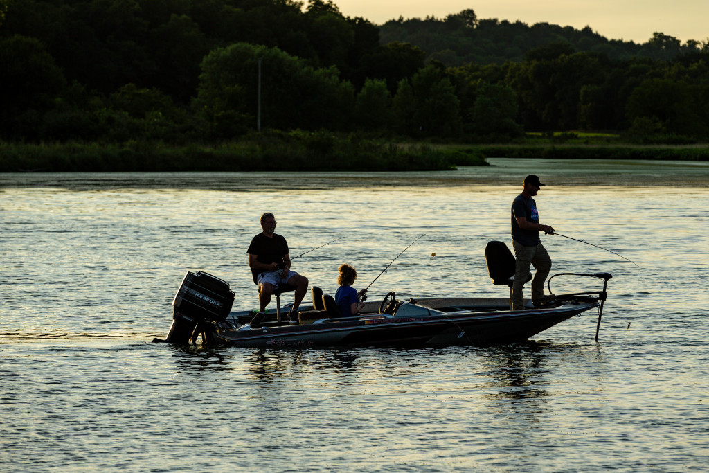 Three people fishing in a boat.