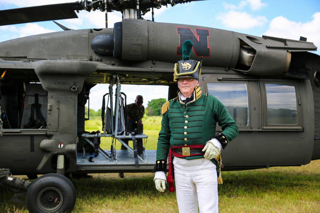 Living history volunteer Bob Baker posing in front of a Black Hawk helicopter.