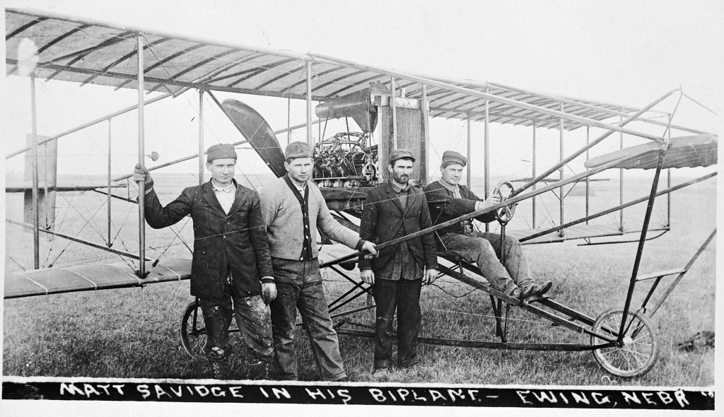 Four men sit on the wings of one of the first planes