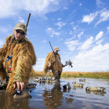 Waterfowl hunters set up decoys in a flooded cornfield.