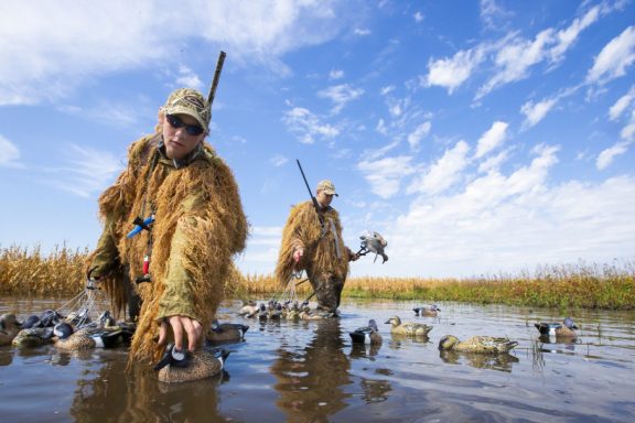 Waterfowl hunters set up decoys in a flooded cornfield.