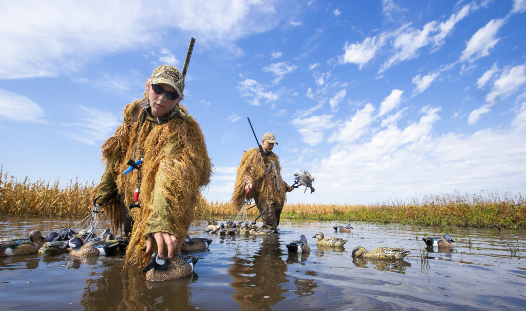 Waterfowl hunters set up decoys in a flooded cornfield.