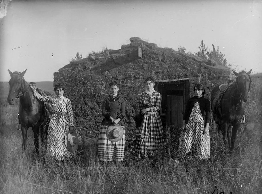 Four sisters pose in front of a sod house on the Nebraska prairie in 1886.