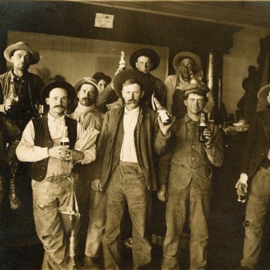 Men pose for the camera with their beer bottles during the Prohibition era in this sepia-toned photo