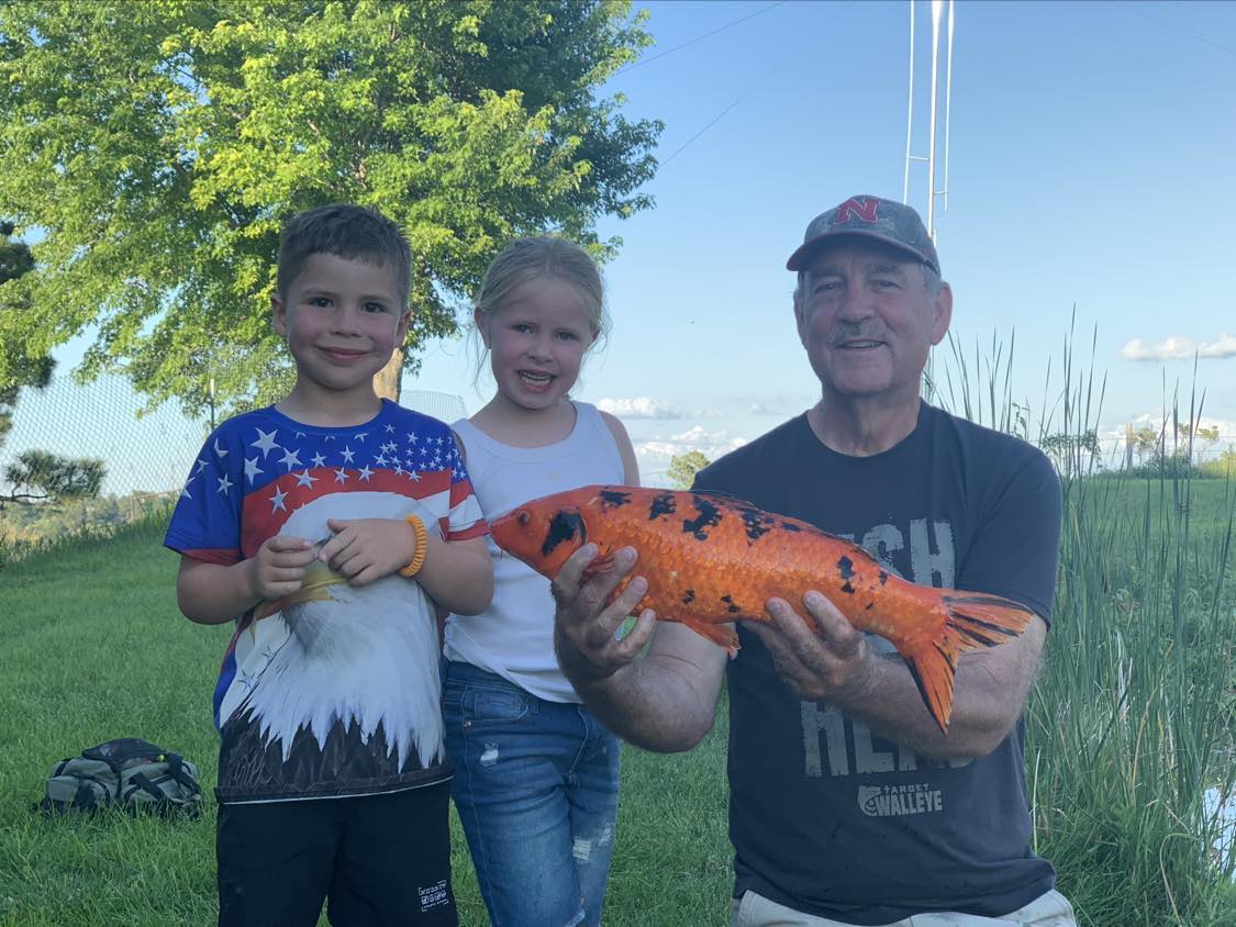 a man and two children holding a koi fish