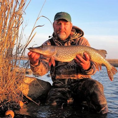 A man holds a northern pike caught at a Nebraska reservoir in early spring.