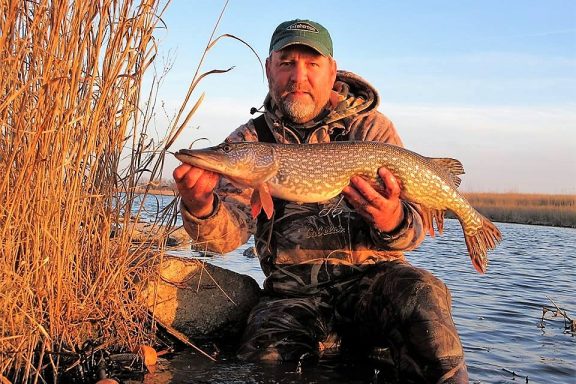 A man holds a northern pike caught at a Nebraska reservoir in early spring.