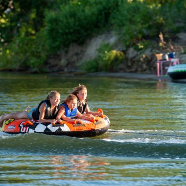 Girls on a tube being pulled by a boat.