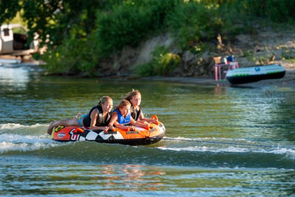 Girls on a tube being pulled by a boat.