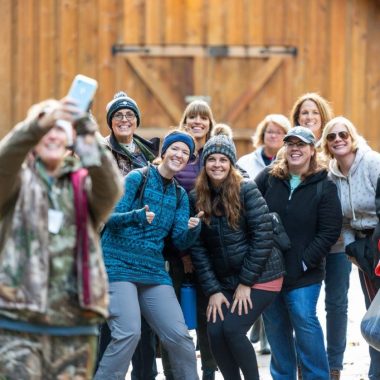 A group of women pose for a photo at an outdoor workshop.