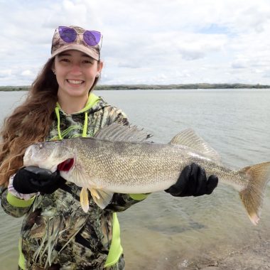 A girl smiles as she holds up a large walleye she caught while fishing in Nebraska.