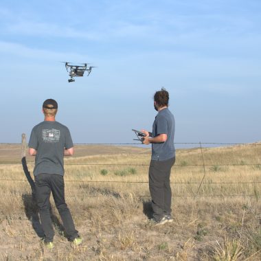 Two men fly a drone.