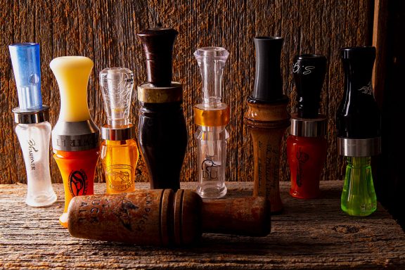 Display of duck calls on a wooden shelf.