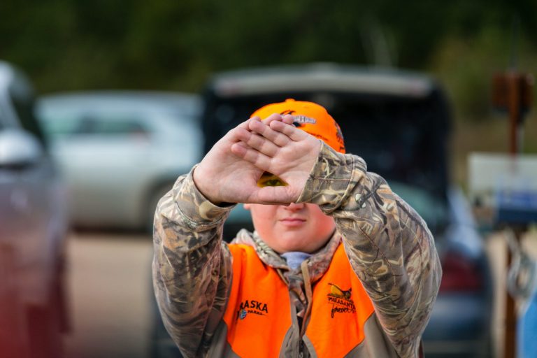 A youth hunter uses his hands to line up his eye for target shooting practice.