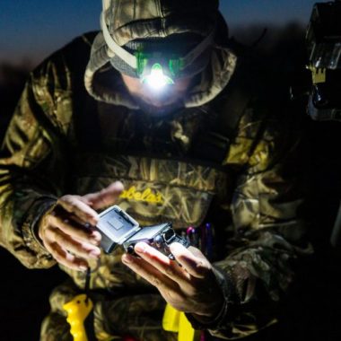 A hunter inspects his GoPro camera with a head lamp in the early morning.