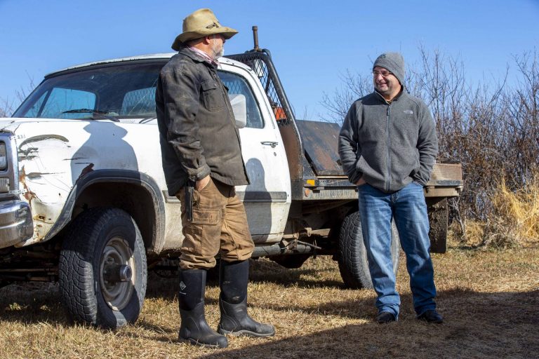 Ranchers having a conversation outside a pickup truck.