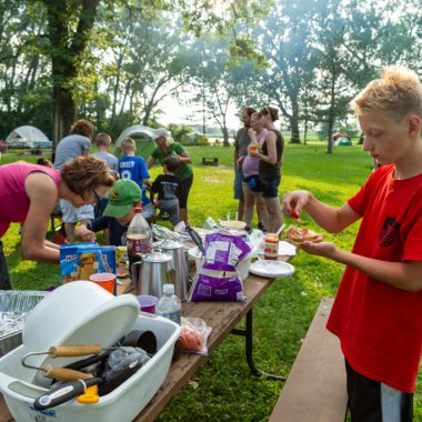 Campers preparing lunch at a picnic table.