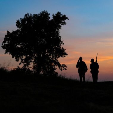 Silhouette of man and woman walking at sundown after shooting doves.