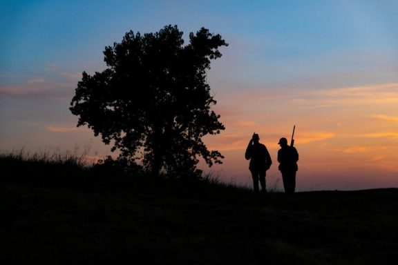 Silhouette of man and woman walking at sundown after shooting doves.