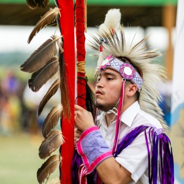 A male powwow dancer holding the Ponca eagle staff during Grand Entry.