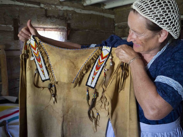 A woman holds up a Native American leather top.