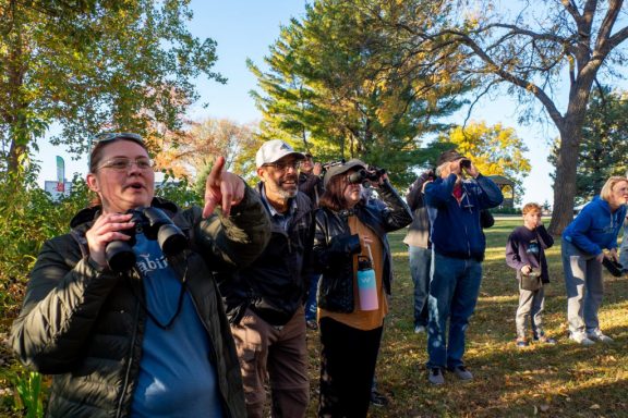 A group of people birding with binoculars.