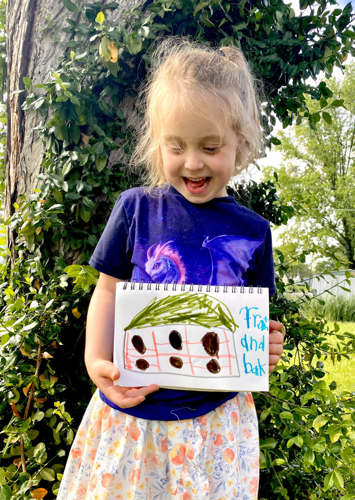 A little girl holds a drawing of a bird "apartment" she designed