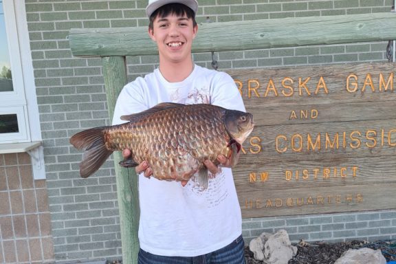 A young man holding a state record goldfish.