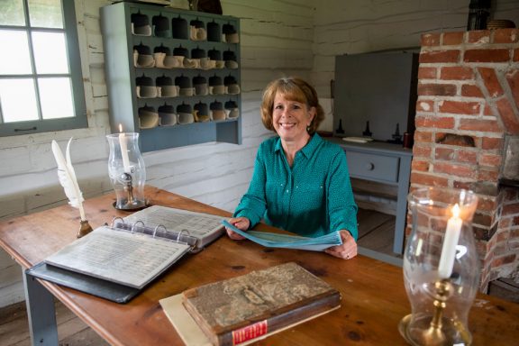 A woman sits at a table with research materials at Fort Atkinson State Historical Park.