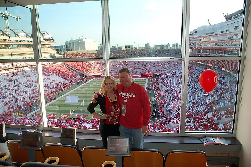 A dad and college-aged daughter pose at a Nebraska Cornhusker Football Game.