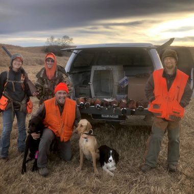 A family poses with harvested pheasants and hunting dog on CRP land in Nebraska.