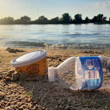 Close-up of litter on a sandy beach on a lake during summer.