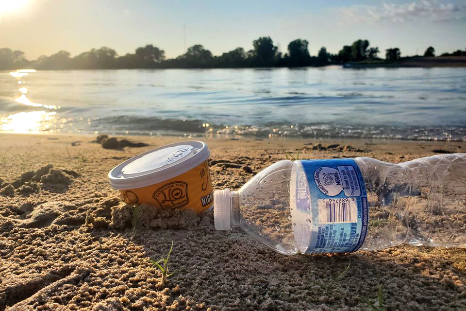 Close-up of litter on a sandy beach on a lake during summer.