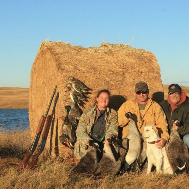 Two men and a woman waterfowl hunting.