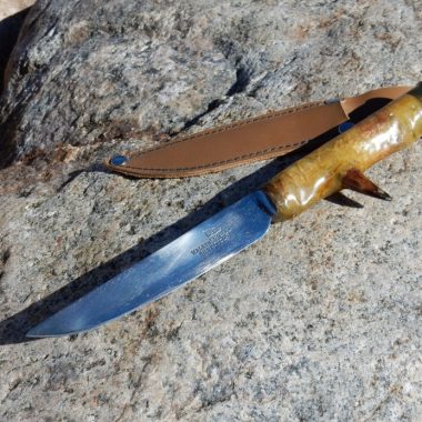 A hand-made turkey hunting knife on a rock.