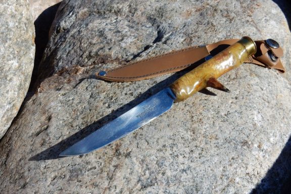 A hand-made turkey hunting knife on a rock.