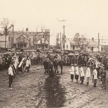 a ditch in the dirt is dug by people wearing vintage Nebraska university clothing