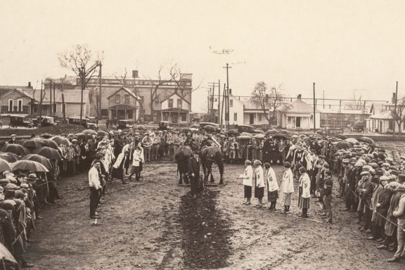 a ditch in the dirt is dug by people wearing vintage Nebraska university clothing