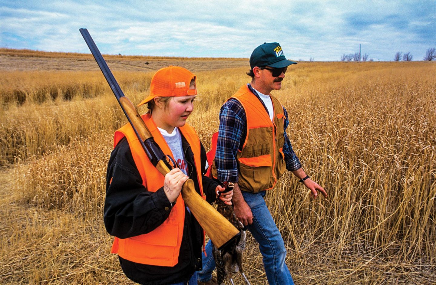 A male hunter education instructor upland hunting with a female youth.