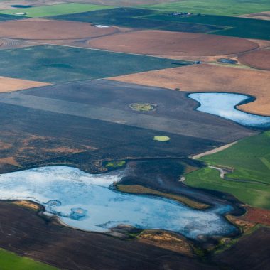 an aerial view of blue wetlands in between farm fields