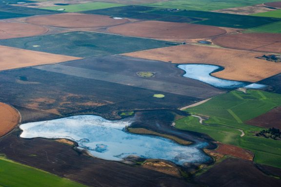 an aerial view of blue wetlands in between farm fields