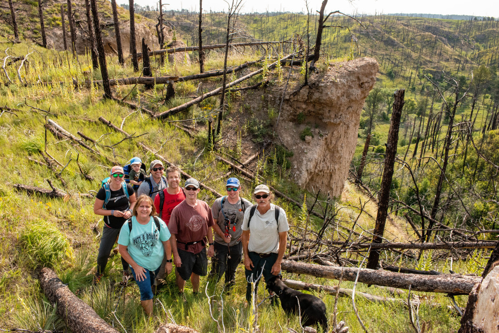 a group of hikers pose near a butte 