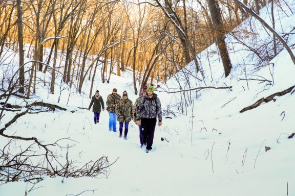 A group of five men and women hike through snow