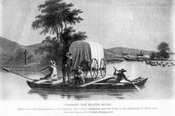 a wooden ferry helps a wagon train across the river